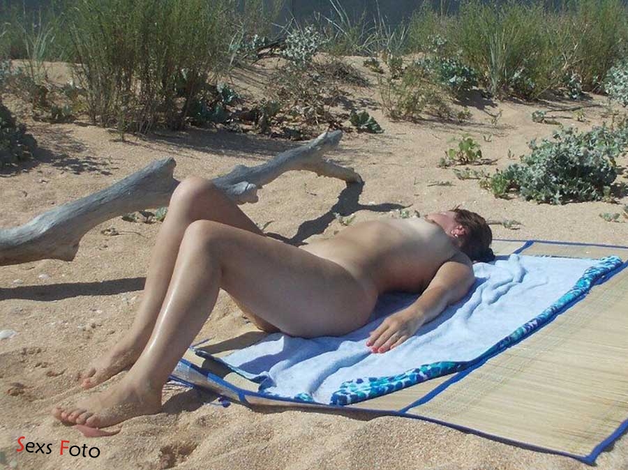 Чёрная нудистка загорает голышом на пляже